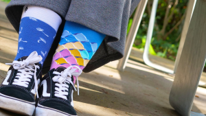 A person sitting in a chair with sneakers and socks visible – the socks are mismatched.